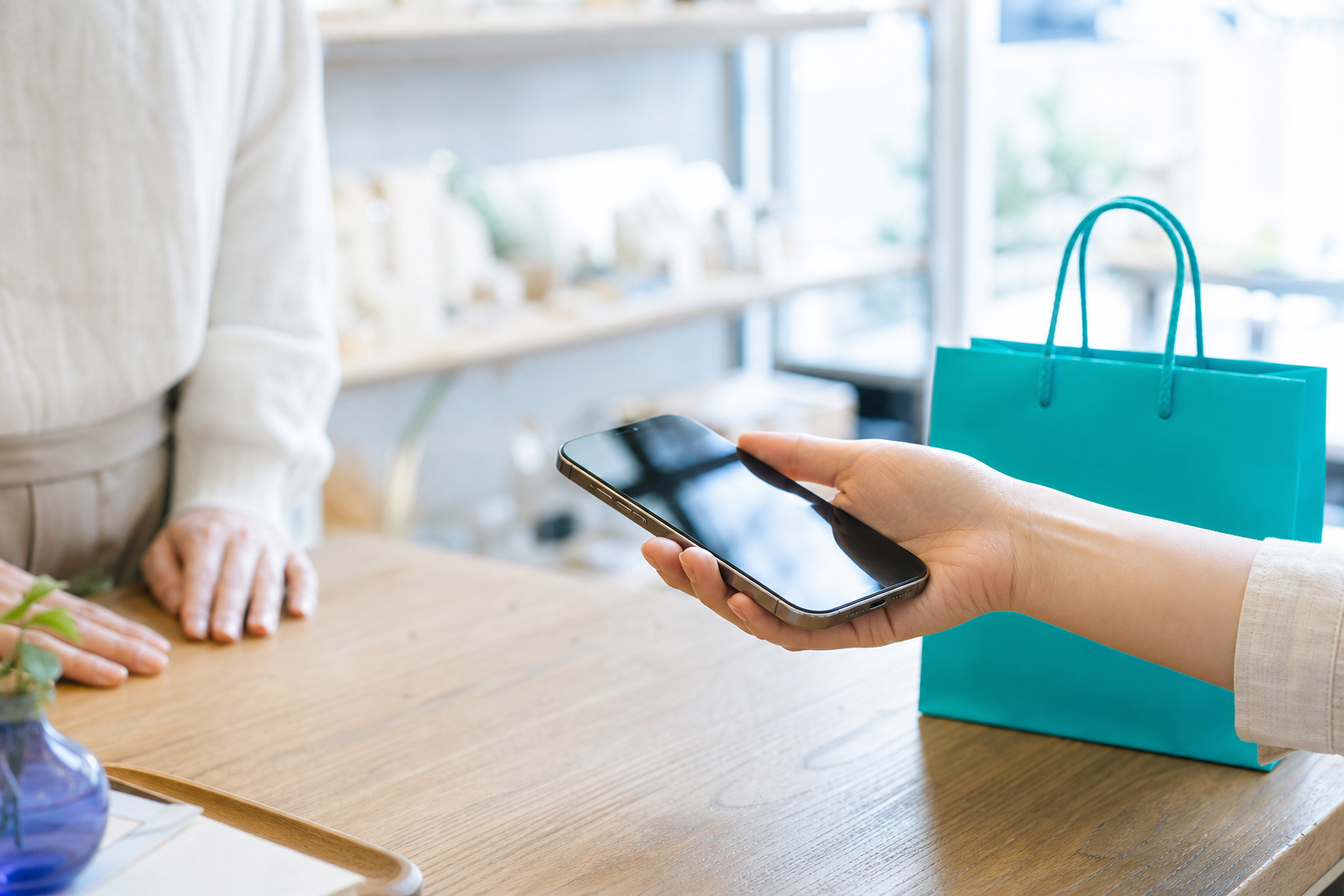 店頭のカウンターでスマートフォンを差し出す手元