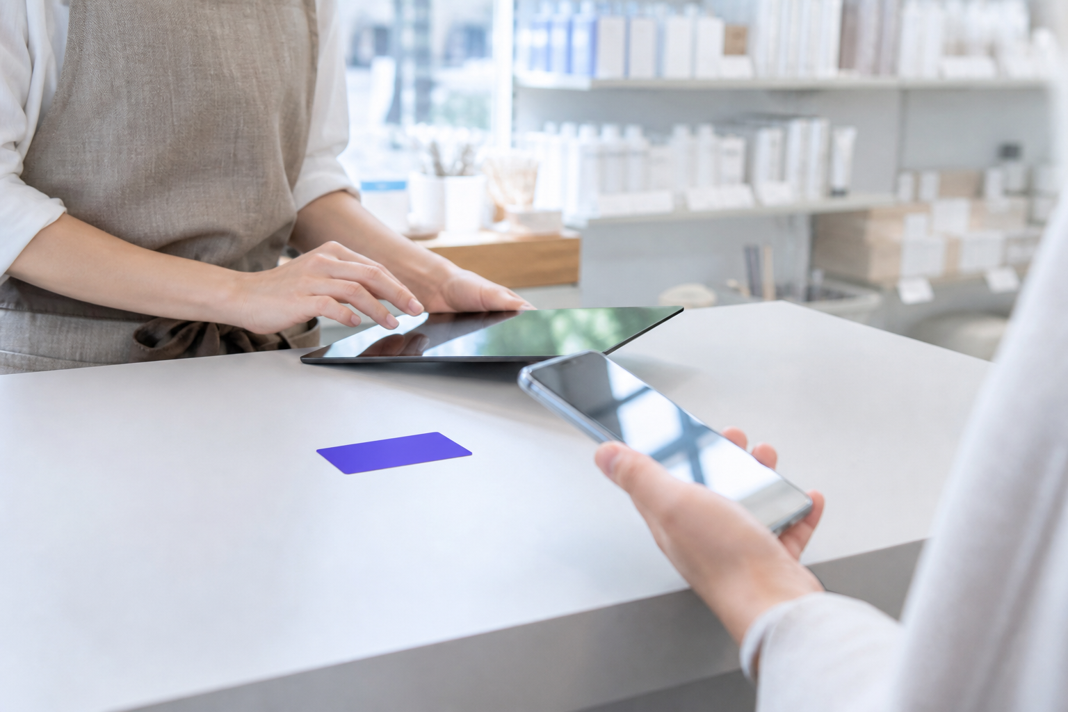 店舗のカウンターで会員証とタブレットを使う接客の様子